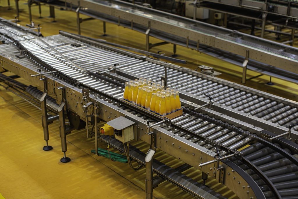 Beverage factory interior. Conveyor flowing with bottles for juice or water.